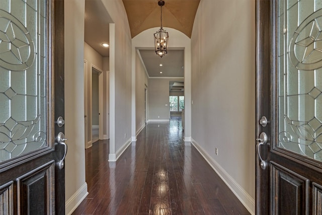 foyer entrance featuring a notable chandelier, dark wood-type flooring, and baseboards