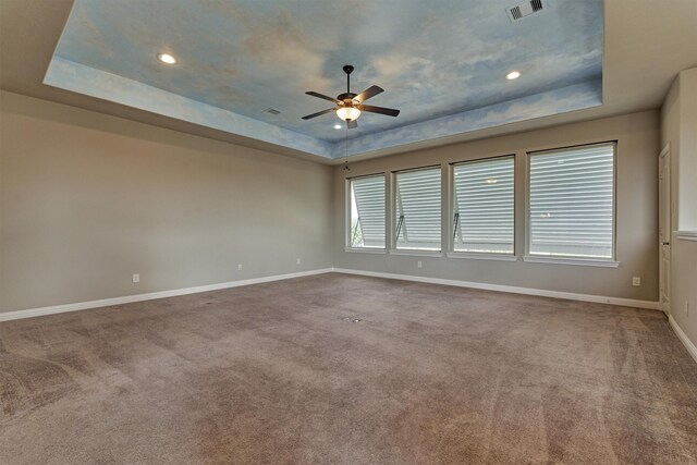 carpeted spare room featuring a tray ceiling and ceiling fan