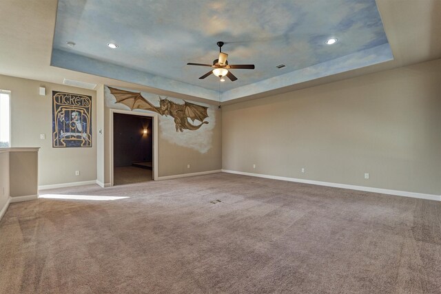 carpeted spare room featuring a raised ceiling and ceiling fan