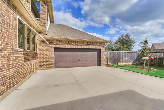 view of side of property featuring concrete driveway, brick siding, an attached garage, and roof with shingles