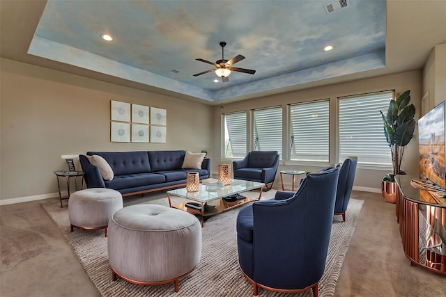 carpeted living area featuring a raised ceiling, visible vents, and baseboards