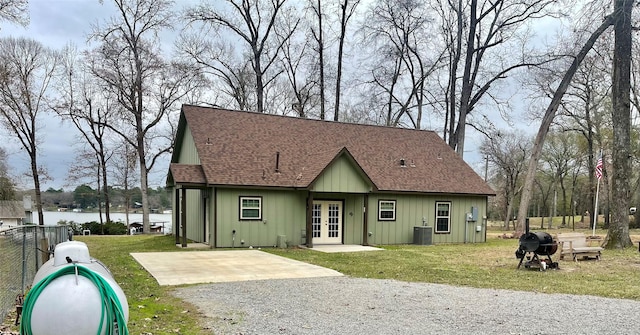 view of front facade with a front yard, french doors, a water view, and cooling unit