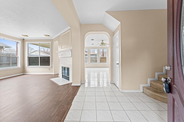 unfurnished living room featuring a tile fireplace, ceiling fan, and light tile patterned floors