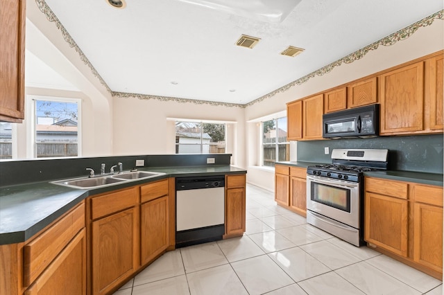 kitchen featuring dishwasher, sink, stainless steel gas range, light tile patterned floors, and tasteful backsplash