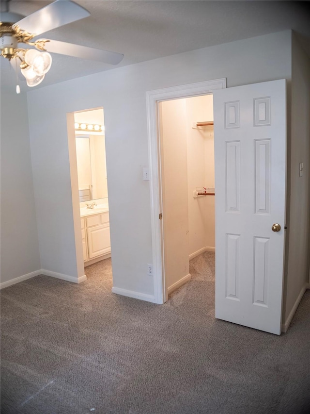 unfurnished bedroom with carpet flooring, ceiling fan, a walk in closet, and a closet