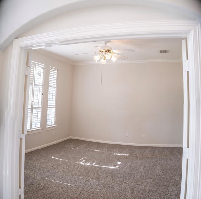 empty room with ceiling fan, carpet floors, and crown molding