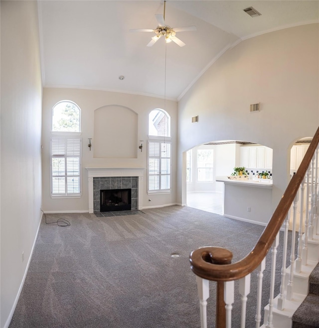 unfurnished living room featuring carpet flooring, a tile fireplace, ceiling fan, and high vaulted ceiling