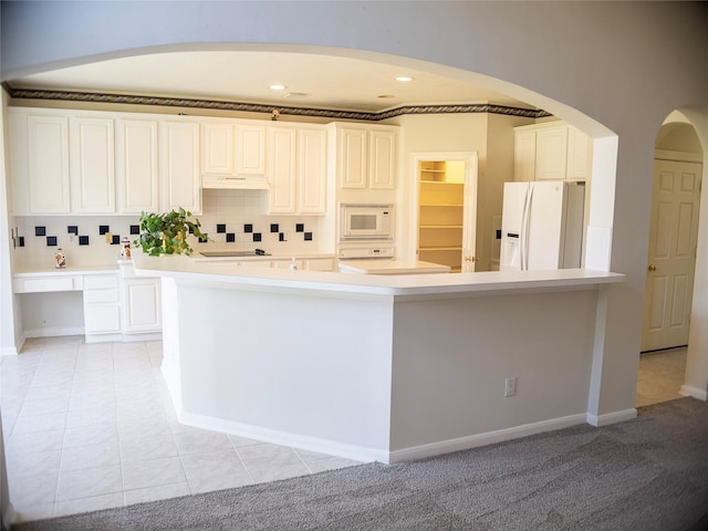 kitchen with a kitchen island, tasteful backsplash, light colored carpet, white appliances, and white cabinets