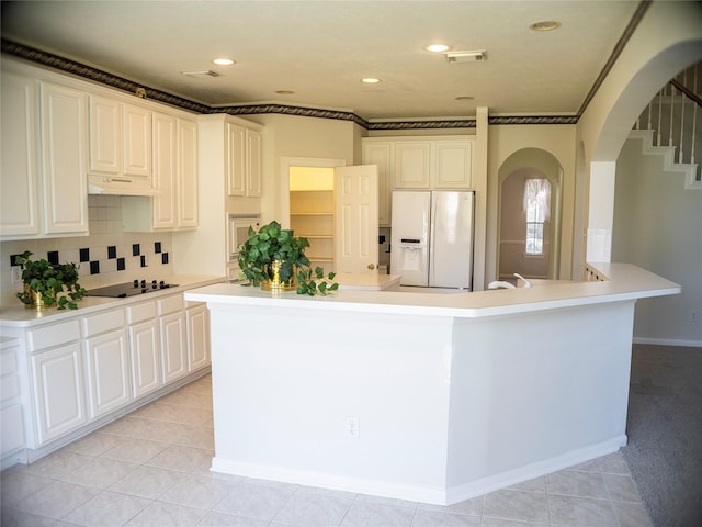 kitchen featuring backsplash, white cabinets, white appliances, and an island with sink