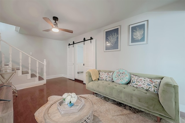 living room with ceiling fan, a barn door, and dark hardwood / wood-style flooring