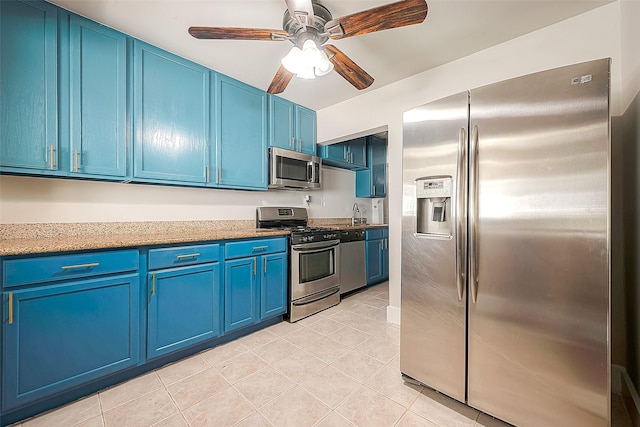 kitchen with ceiling fan, blue cabinets, light tile patterned floors, and appliances with stainless steel finishes