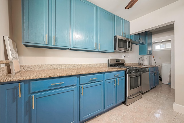 kitchen featuring sink, ceiling fan, light tile patterned floors, blue cabinetry, and stainless steel appliances