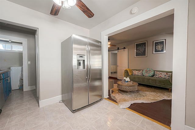 kitchen featuring ceiling fan, a barn door, light tile patterned floors, and stainless steel refrigerator with ice dispenser