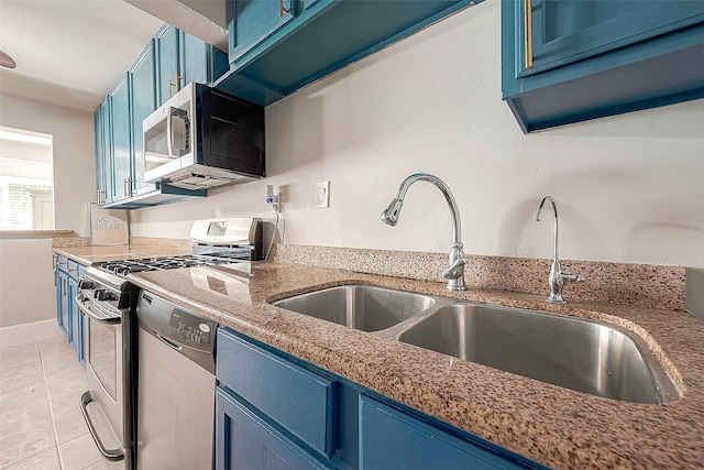 kitchen with blue cabinetry, appliances with stainless steel finishes, light tile patterned floors, and sink