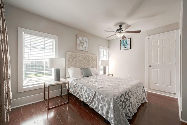 bedroom with ceiling fan, dark wood-type flooring, and multiple windows