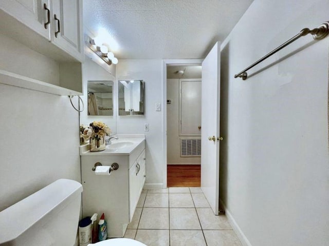 bathroom with toilet, vanity, a textured ceiling, and tile patterned floors