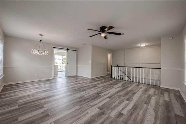 spare room featuring hardwood / wood-style floors and ceiling fan with notable chandelier