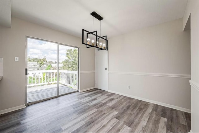 unfurnished dining area with a notable chandelier and wood-type flooring