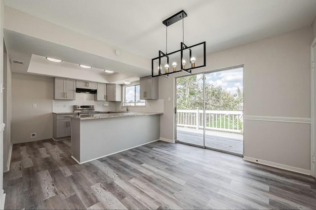 kitchen with gray cabinetry, pendant lighting, stainless steel range, dark hardwood / wood-style flooring, and kitchen peninsula