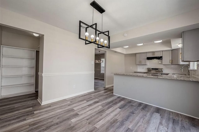 kitchen featuring kitchen peninsula, gray cabinetry, sink, dark hardwood / wood-style floors, and hanging light fixtures