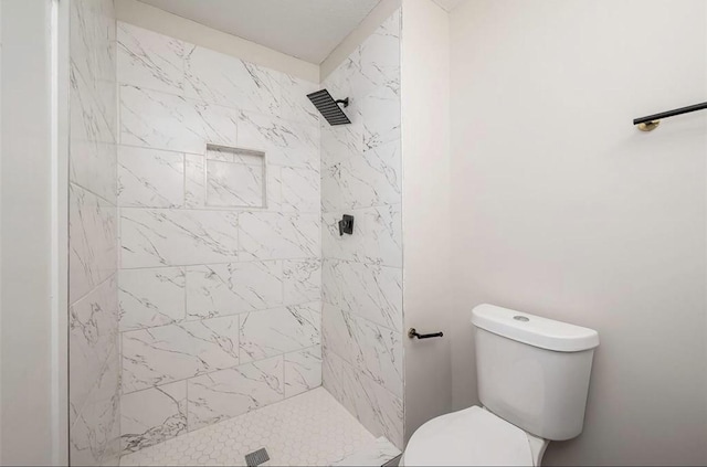 bathroom with a tile shower and toilet