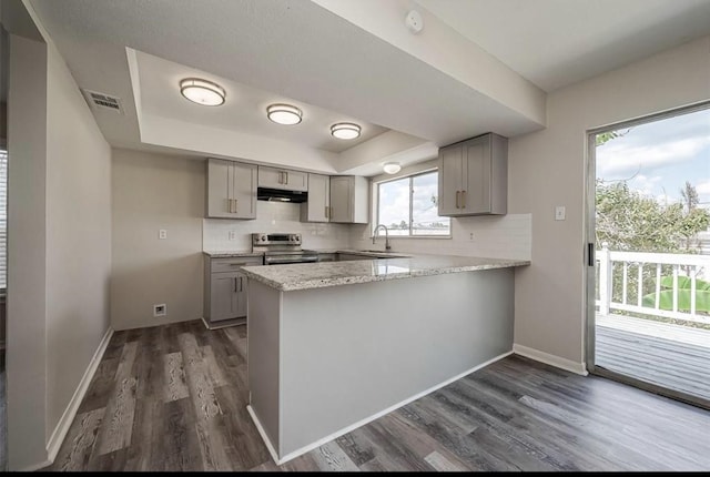 kitchen featuring stainless steel electric stove, gray cabinets, a tray ceiling, dark hardwood / wood-style flooring, and kitchen peninsula