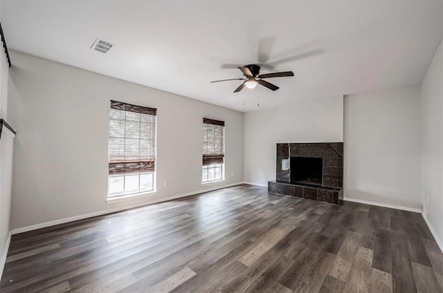 unfurnished living room with a tiled fireplace, ceiling fan, and dark hardwood / wood-style flooring