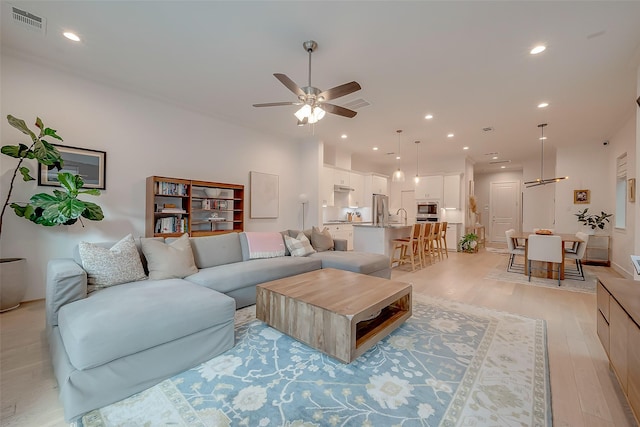 living room with sink, ceiling fan, and light hardwood / wood-style flooring