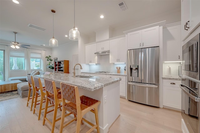 kitchen featuring sink, stainless steel appliances, white cabinets, and a kitchen bar