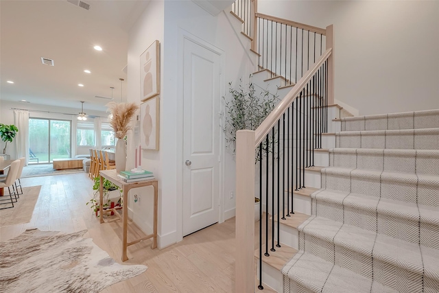 staircase with ceiling fan and hardwood / wood-style flooring