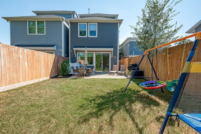 rear view of property featuring a playground, a patio, and a yard