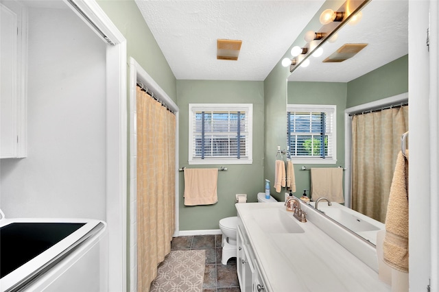 bathroom with washer / clothes dryer, vanity, a textured ceiling, and toilet