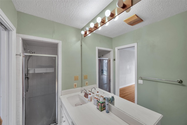 bathroom featuring a textured ceiling, vanity, and an enclosed shower