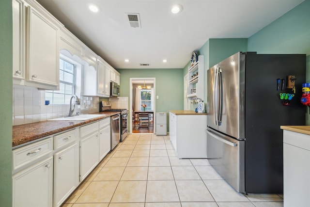 kitchen with white cabinetry, sink, decorative backsplash, light tile patterned floors, and appliances with stainless steel finishes