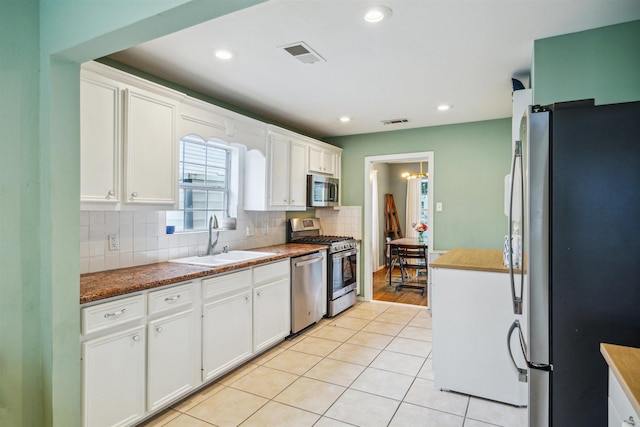 kitchen featuring sink, light tile patterned floors, decorative backsplash, white cabinets, and appliances with stainless steel finishes