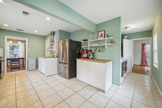 kitchen featuring white cabinets, stainless steel appliances, a notable chandelier, and light tile patterned flooring