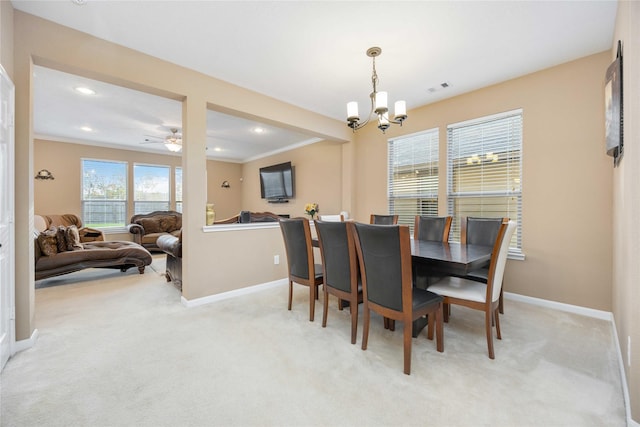 carpeted dining area with ceiling fan with notable chandelier and crown molding