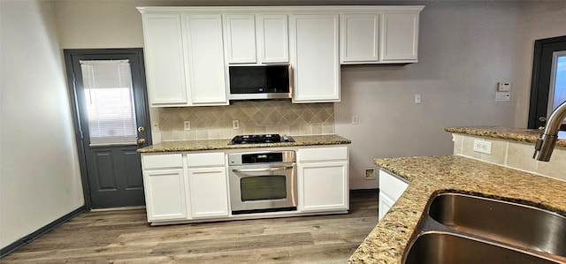 kitchen with sink, light stone countertops, tasteful backsplash, white cabinetry, and stainless steel appliances