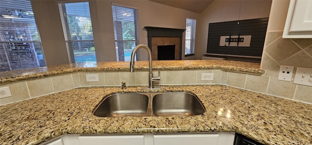 kitchen with sink, backsplash, lofted ceiling, stone countertops, and white cabinets