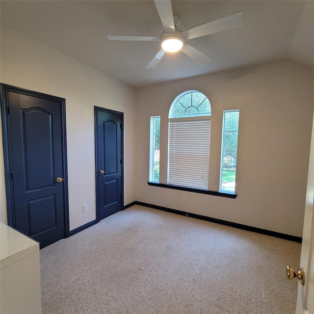 empty room featuring light carpet, vaulted ceiling, and ceiling fan