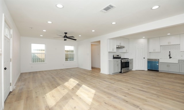 kitchen featuring backsplash, stainless steel appliances, ceiling fan, sink, and light hardwood / wood-style flooring