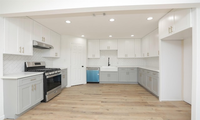 kitchen featuring decorative backsplash, appliances with stainless steel finishes, light wood-type flooring, sink, and white cabinetry