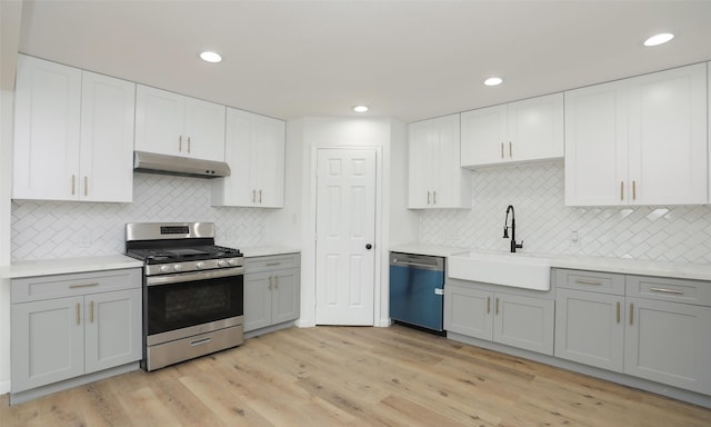 kitchen with backsplash, sink, light hardwood / wood-style flooring, and appliances with stainless steel finishes