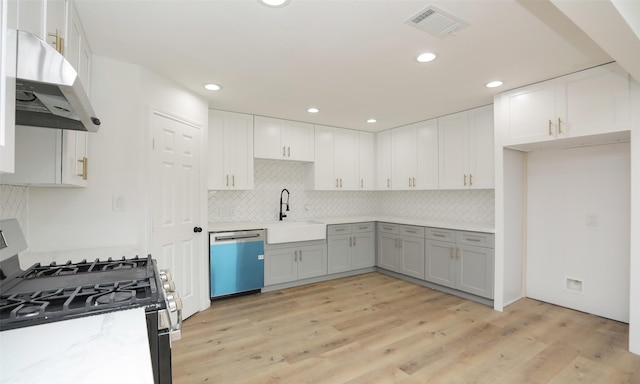 kitchen with sink, appliances with stainless steel finishes, gray cabinets, white cabinets, and light wood-type flooring