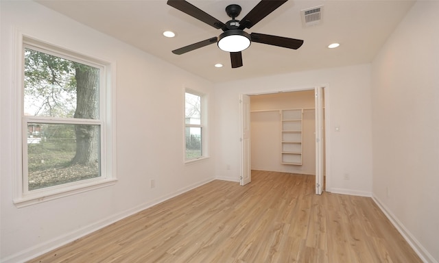 unfurnished bedroom featuring multiple windows, light wood-type flooring, and ceiling fan