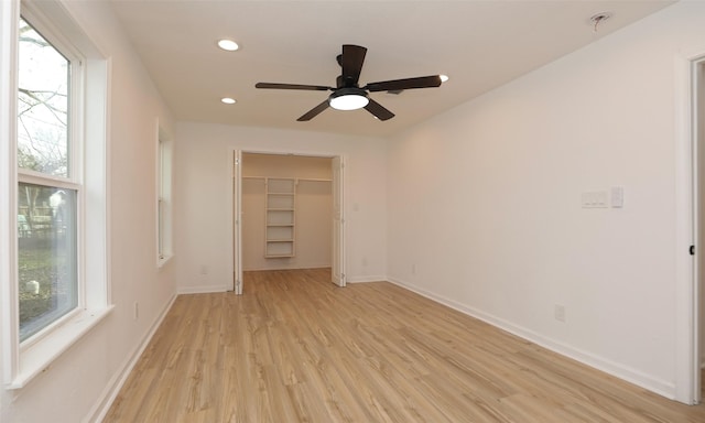 interior space with a walk in closet, light wood-type flooring, a closet, and ceiling fan