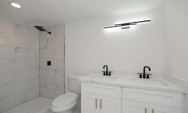 bathroom with a tile shower, vanity, and toilet