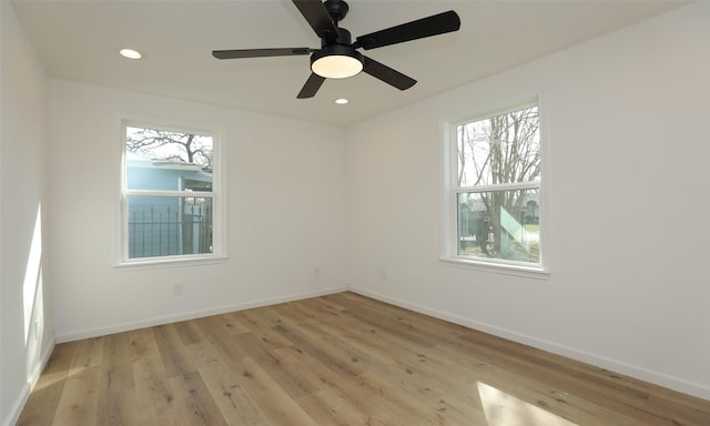 empty room featuring ceiling fan, light wood-type flooring, and a wealth of natural light