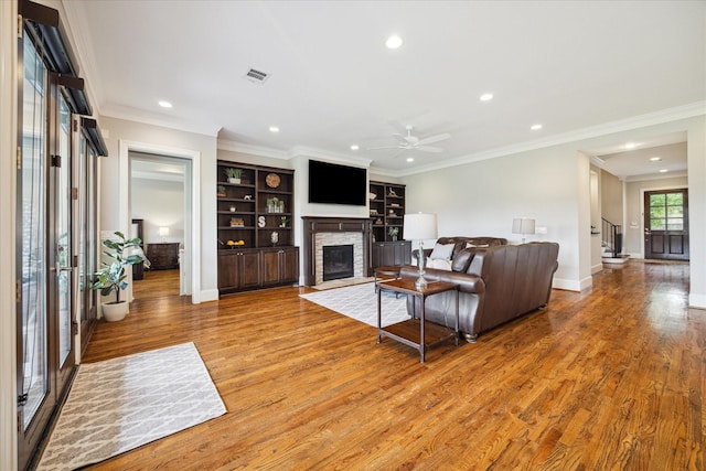 living room featuring a fireplace, hardwood / wood-style floors, and crown molding