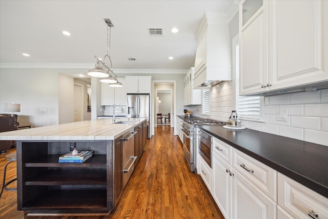 kitchen with a center island with sink, white cabinets, and hanging light fixtures